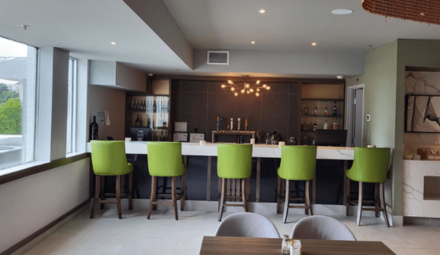 Five green chairs in front of a casual restaurant bar.